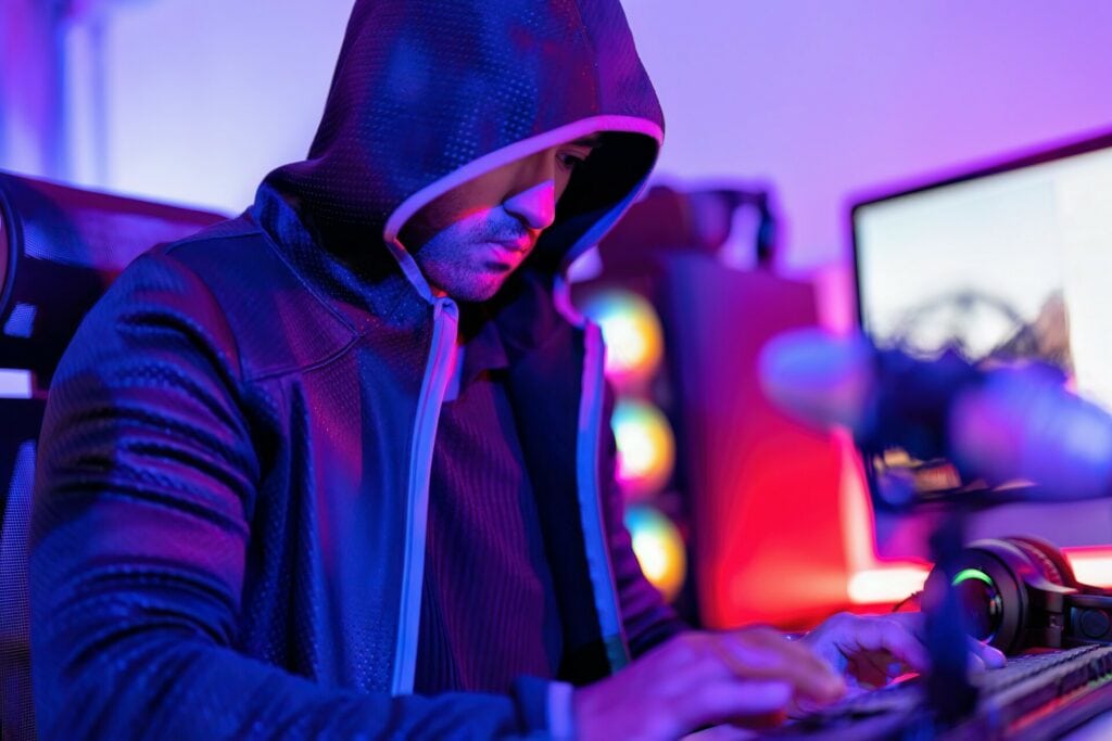 hacker wearing hood jacket typing computer keyboard to phishing steal attack